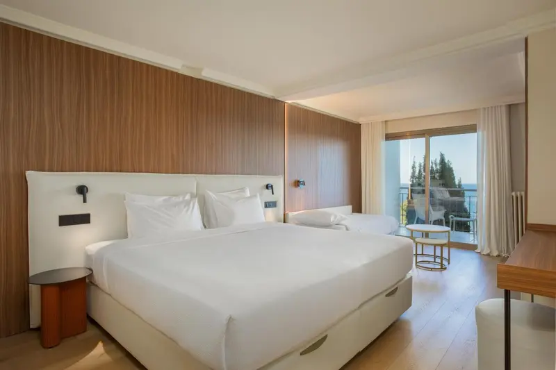 Une chambre lumineuse avec un grand lit et un accès à un balcon.