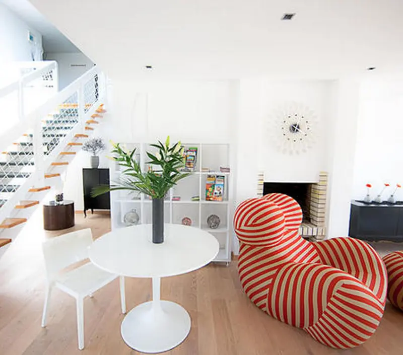 Un salon lumineux avec un escalier moderne et un mobilier design.