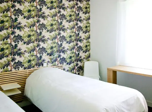 Une chambre lumineuse avec un lit recouvert de draps blancs et un bureau en bois.