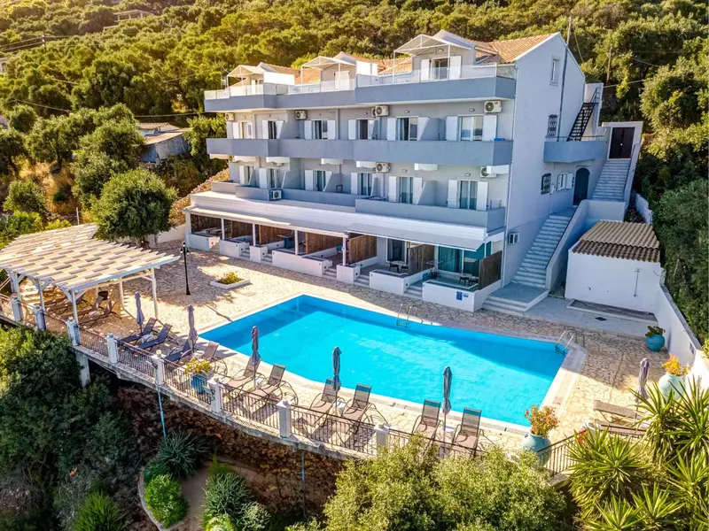 Vue aérienne d'un bâtiment blanc avec une piscine et des transats.