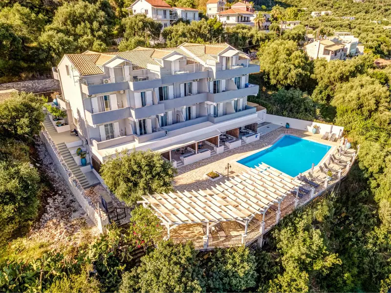 Vue aérienne d'un bâtiment blanc avec des balcons et une piscine en contrebas.