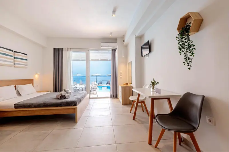 Chambre lumineuse avec un lit double et un espace repas près d'une fenêtre.
