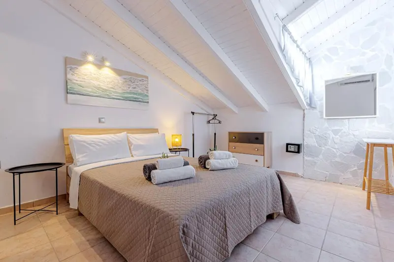 Une chambre mansardée lumineuse avec un lit double et une décoration sobre.