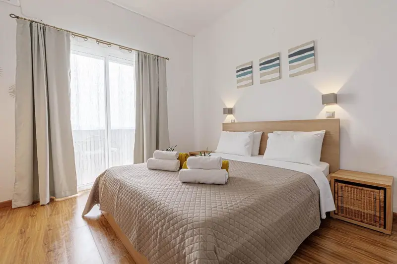 Une chambre lumineuse avec un grand lit et un accès à un balcon.