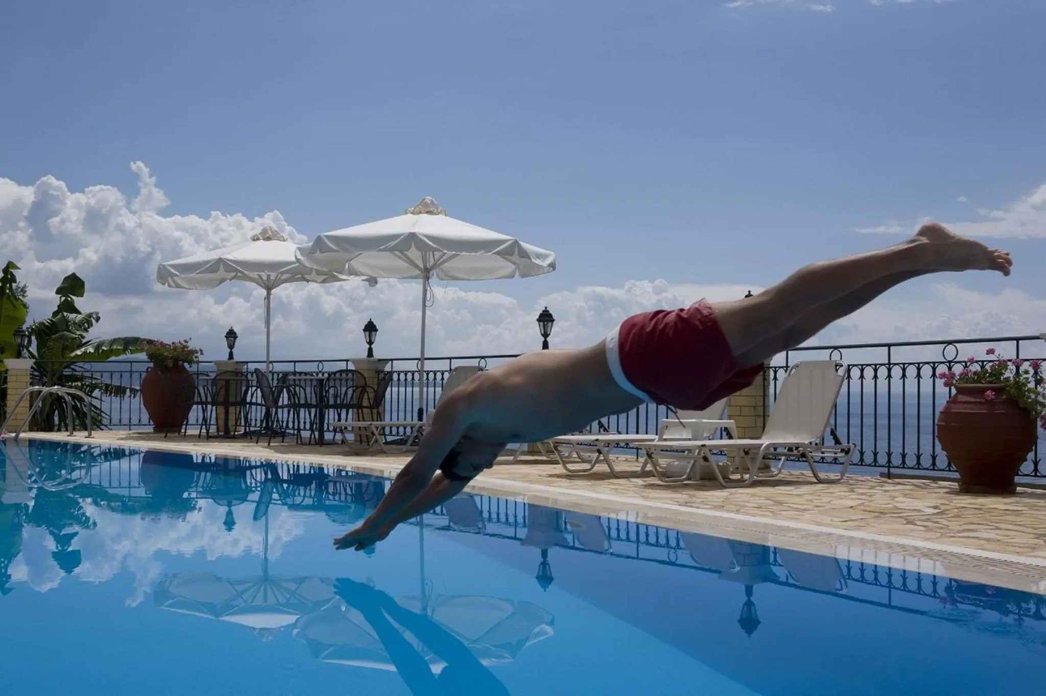 Une personne plonge dans une piscine en bord de mer.