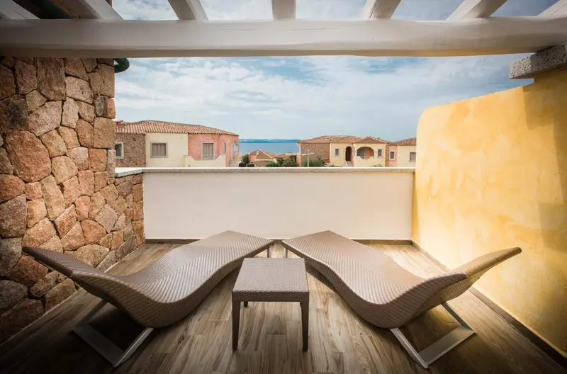 Deux chaises longues invitent à la détente sur une terrasse ensoleillée avec vue sur la mer.