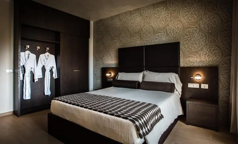 Une chambre moderne avec un grand lit et des peignoirs suspendus.