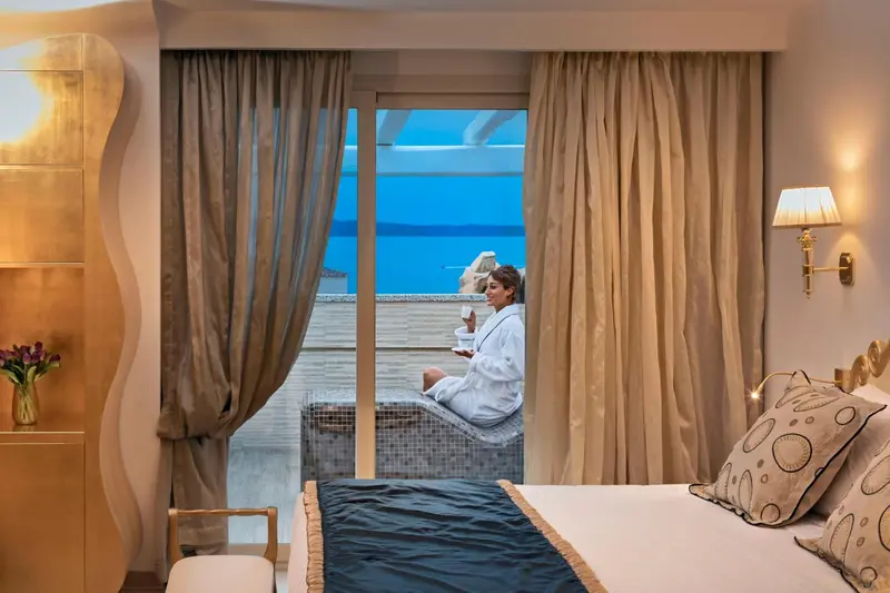 Une femme assise sur une terrasse avec vue sur la mer.