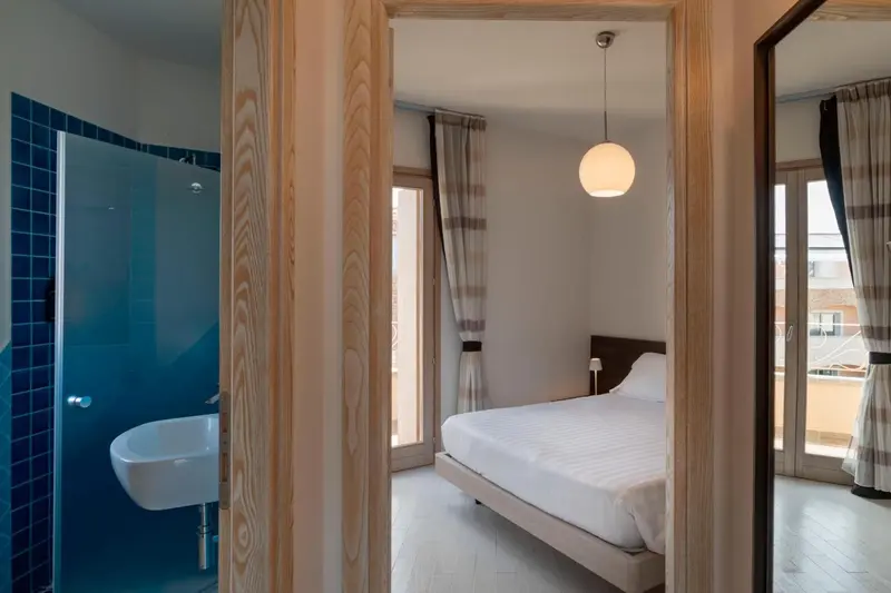 Une chambre lumineuse avec un lit blanc et une salle de bain moderne.