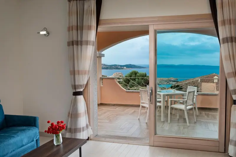 Une vue sur la mer est visible depuis une terrasse avec table et chaises.
