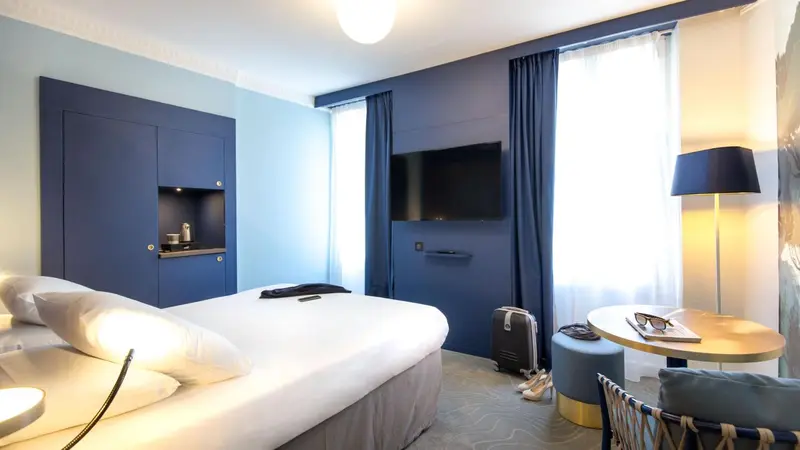 Une chambre d'hôtel moderne avec un lit blanc et une décoration bleue.