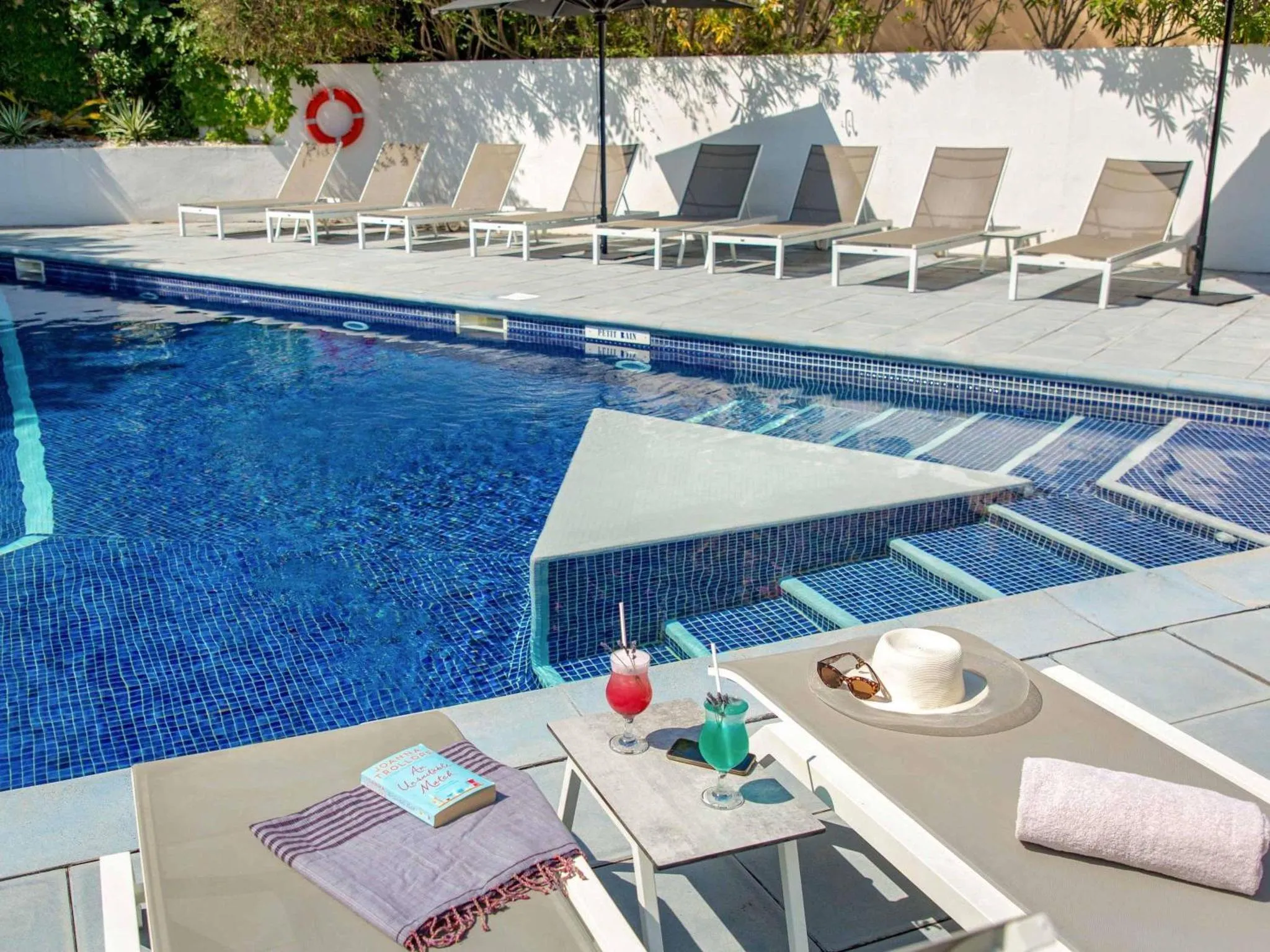 Transats et table basse au bord d'une piscine bleue.
