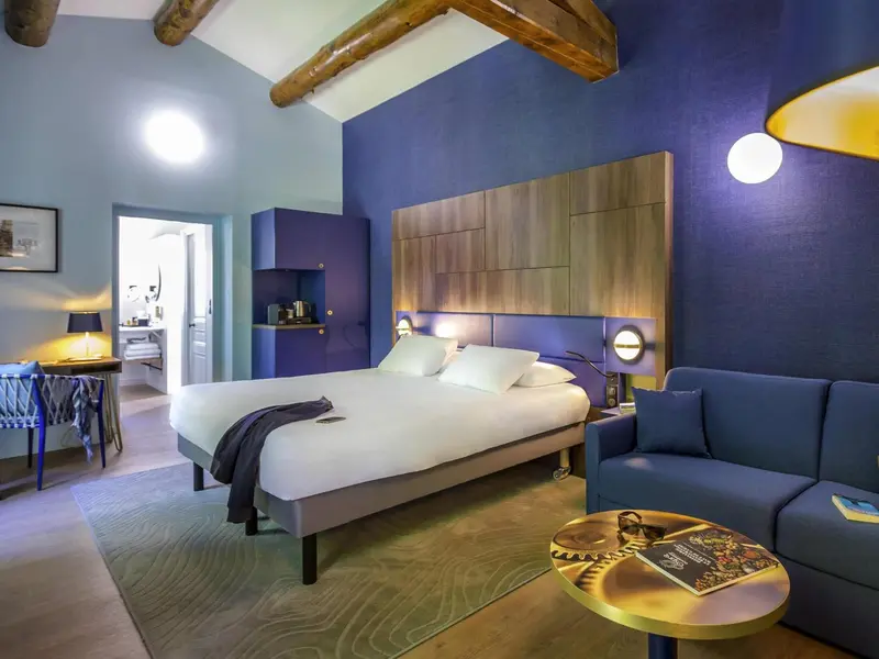 Une chambre lumineuse avec un grand lit et un coin salon.