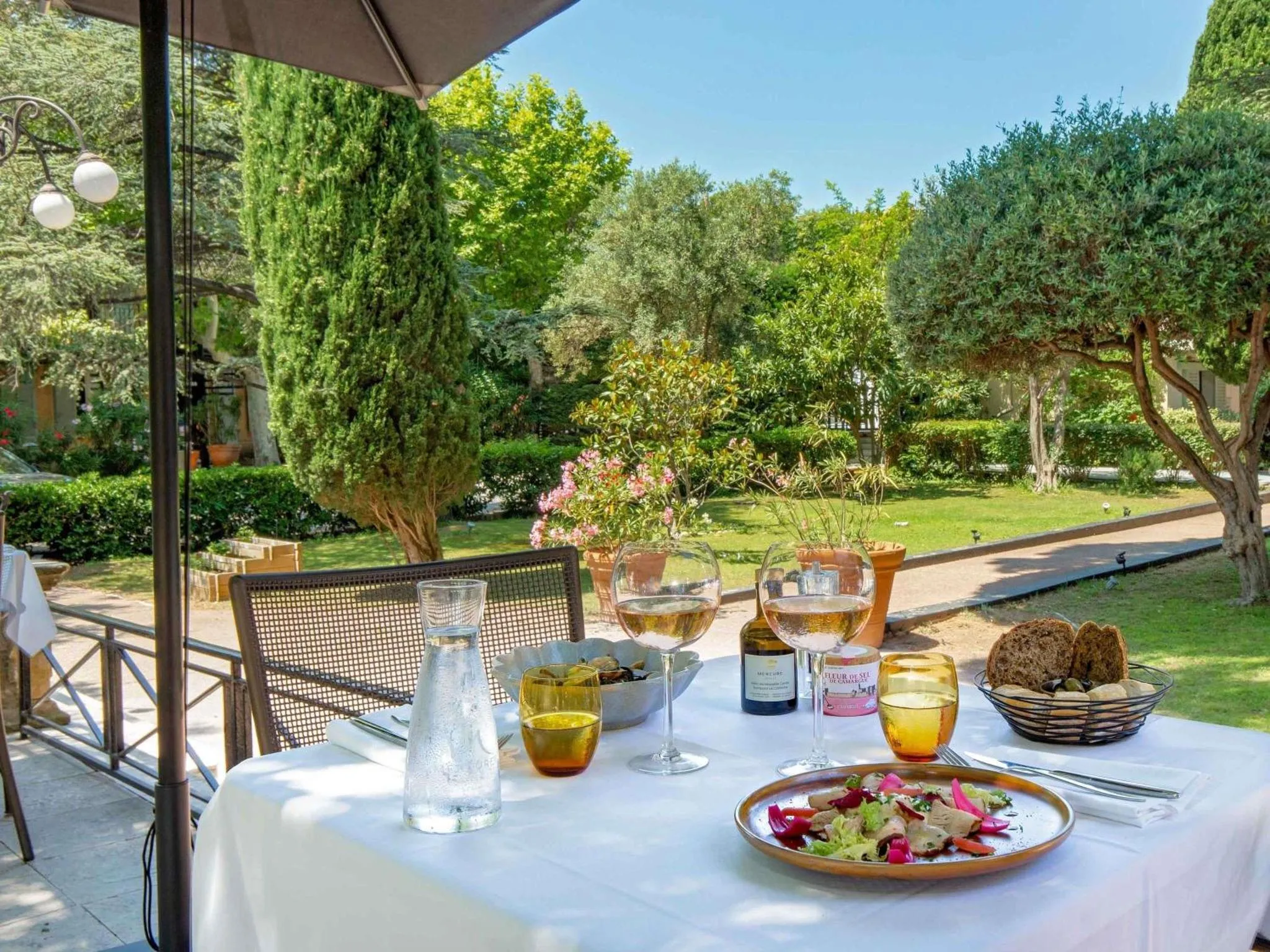 Une table est dressée avec des plats et des boissons sur une terrasse ensoleillée.