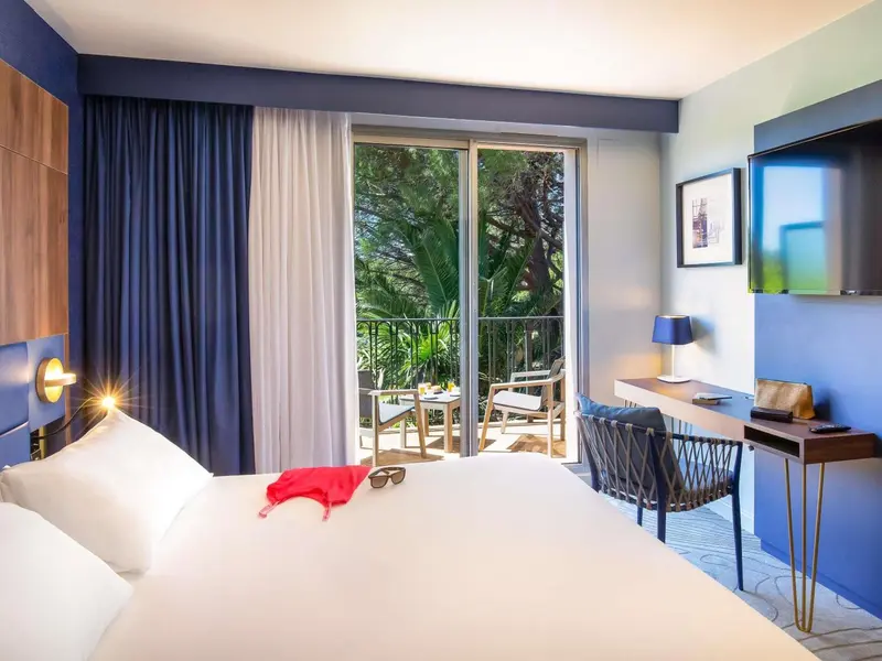 Une chambre lumineuse avec un lit et un accès à une terrasse.