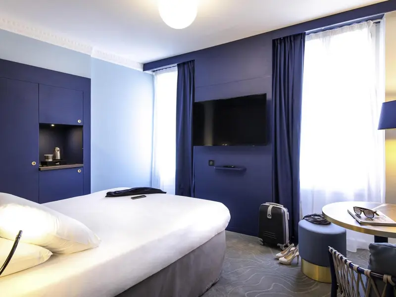 Une chambre d'hôtel moderne avec un lit blanc et un mur bleu.
