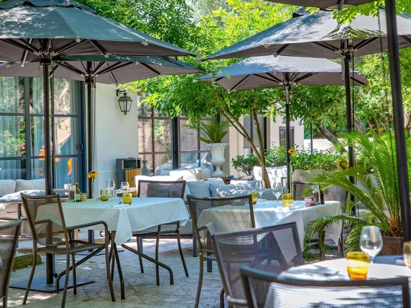 Terrasse ombragée avec tables nappées et chaises.
