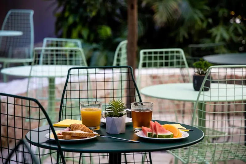 Une table ronde avec un petit-déjeuner est mise en scène sur une terrasse.