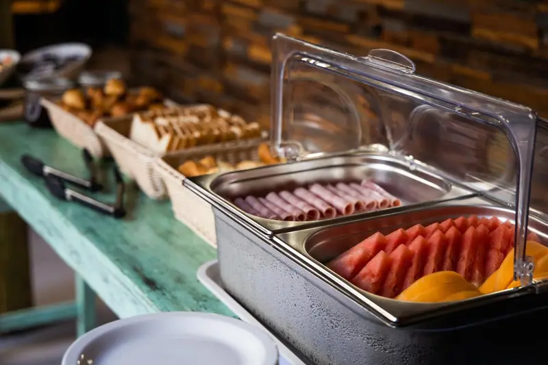 Un buffet propose des viennoiseries, des charcuteries et des fruits frais.