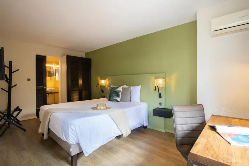 Une chambre lumineuse avec un grand lit et un bureau.