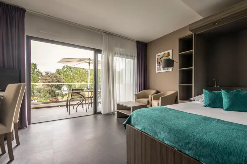 Une chambre lumineuse s'ouvre sur une terrasse avec mobilier.