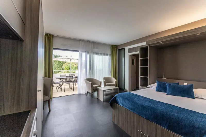 Une chambre avec un lit double et un accès à une terrasse aménagée.