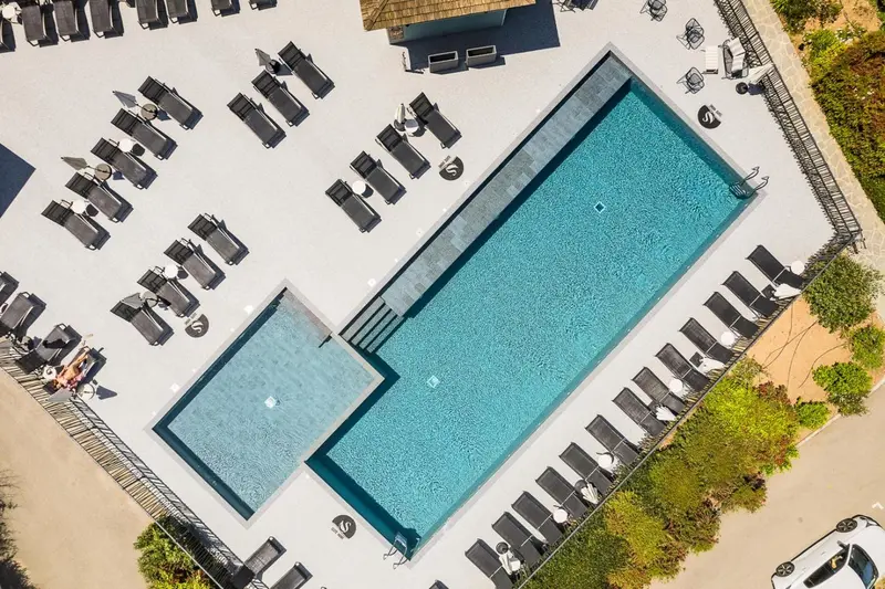 Vue aérienne d'une piscine rectangulaire entourée de chaises longues.
