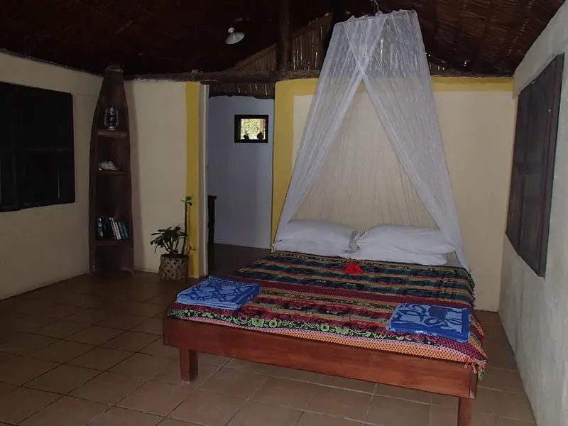 Une chambre avec un lit recouvert d'une moustiquaire et d'une courtepointe colorée.