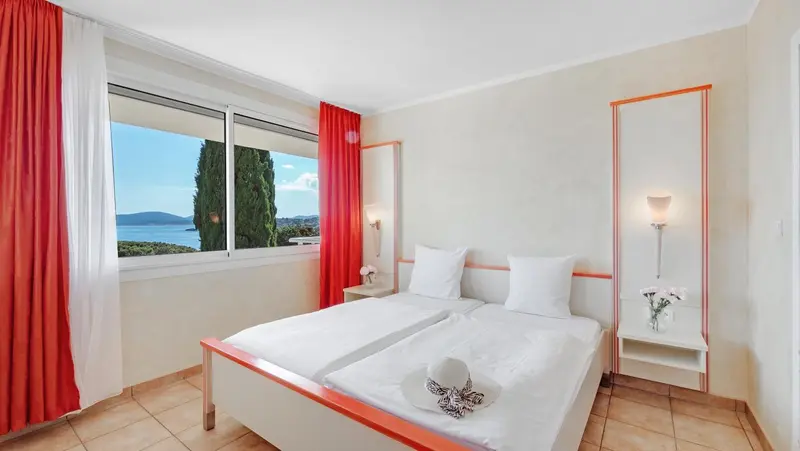 Chambre lumineuse avec vue sur la mer et un lit double.