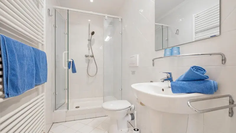 Une salle de bain claire avec douche à l'italienne et lavabo.