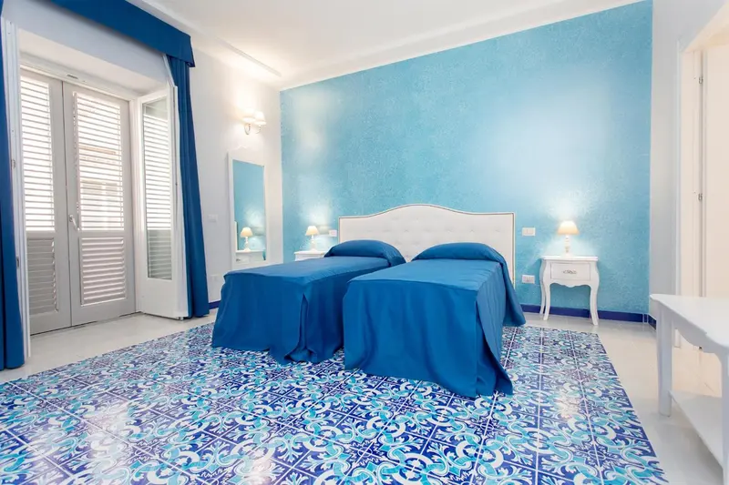 Chambre lumineuse avec deux lits simples et un décor bleu et blanc.