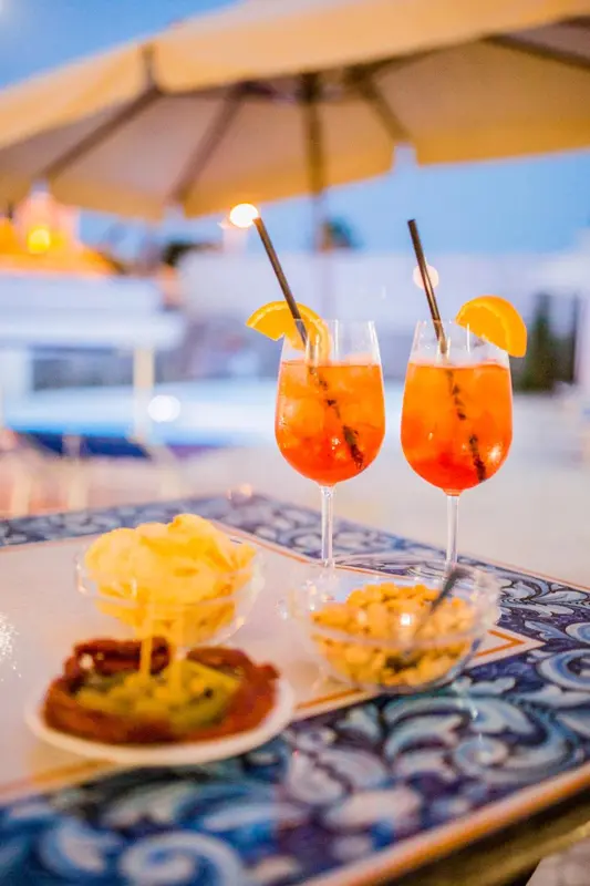 Deux cocktails aux agrumes et des amuse-gueules sont servis sur une table décorée.