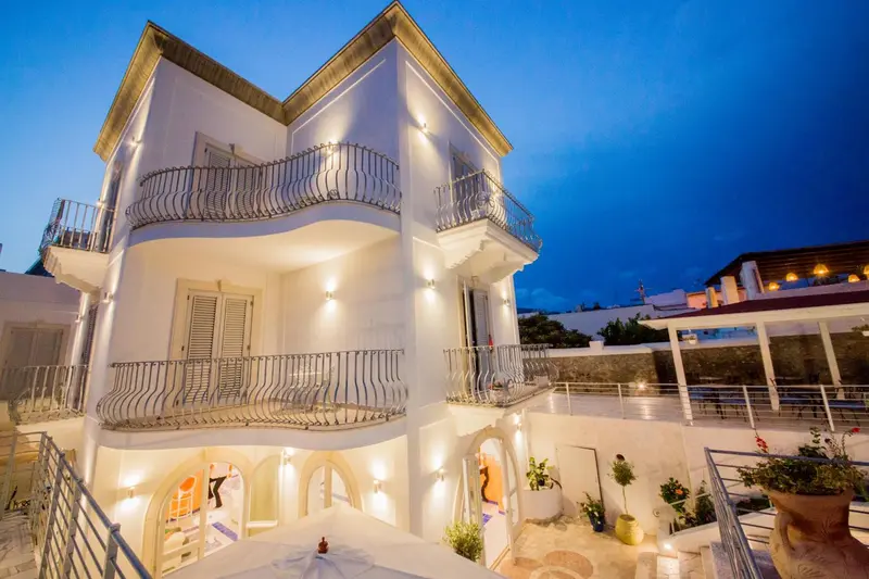 Façade d'un bâtiment blanc illuminé avec des balcons et des jardinières.