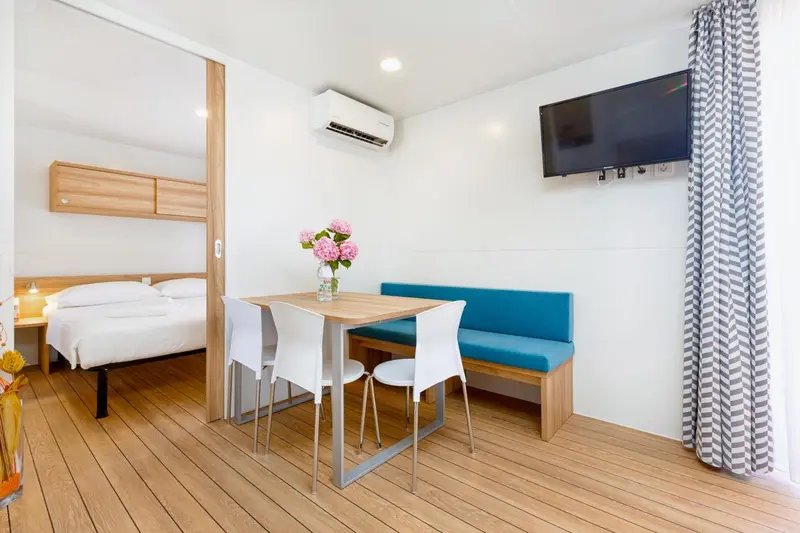 Une chambre lumineuse avec un lit, une table et des assises.