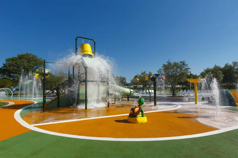 Aire de jeux aquatique avec structure colorée et jets d'eau.