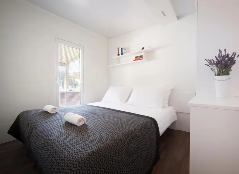 Une chambre lumineuse avec un lit fait et une décoration minimaliste.