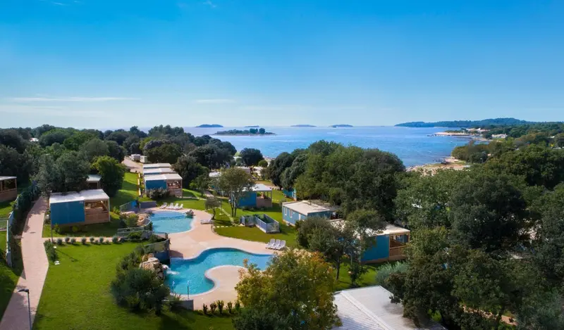 Vue aérienne d'un complexe de vacances avec piscine et végétation luxuriante.