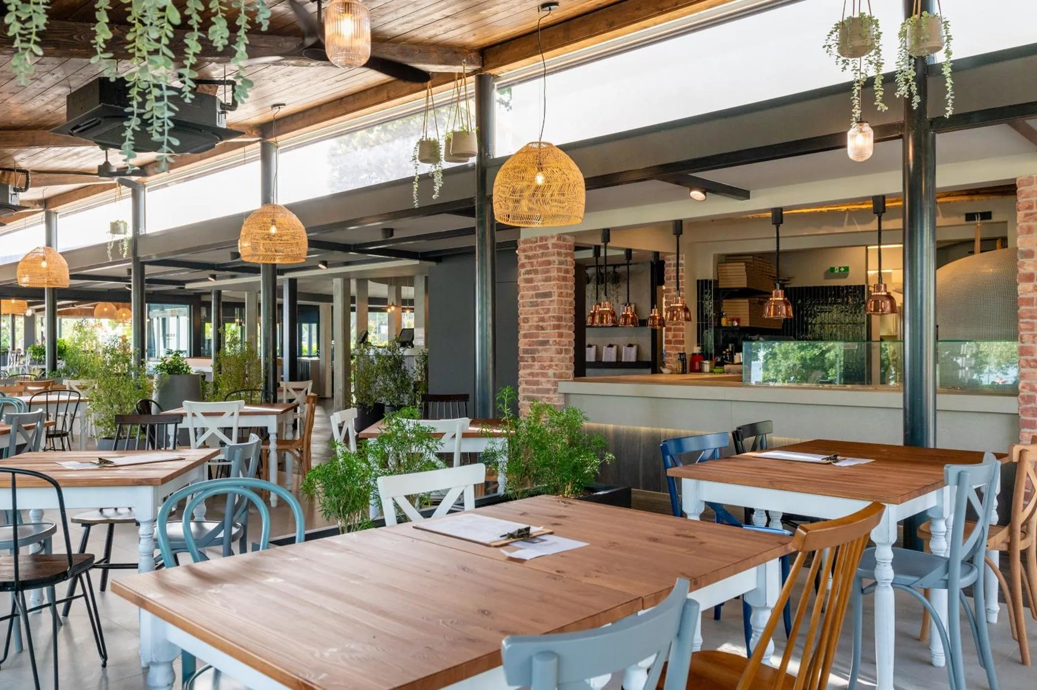 Une salle de restaurant lumineuse avec des tables en bois et des chaises bleues.