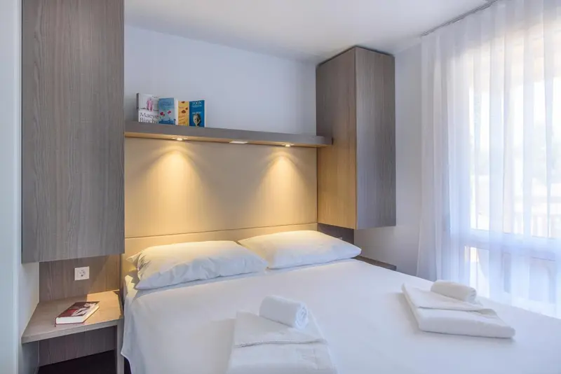 Une chambre lumineuse avec un lit double et des rangements muraux.