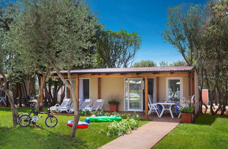 Mobil-home beige avec terrasse et mobilier de jardin.