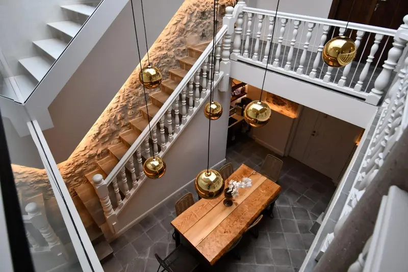 Une table en bois est placée devant un escalier décoré de sphères lumineuses.