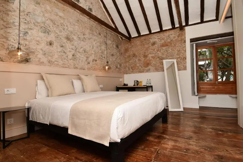 Une chambre à coucher lumineuse avec un lit double et un mur en pierre.