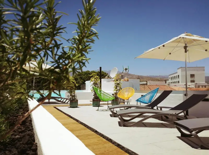 Terrasse avec chaises longues et parasols près d'une piscine.