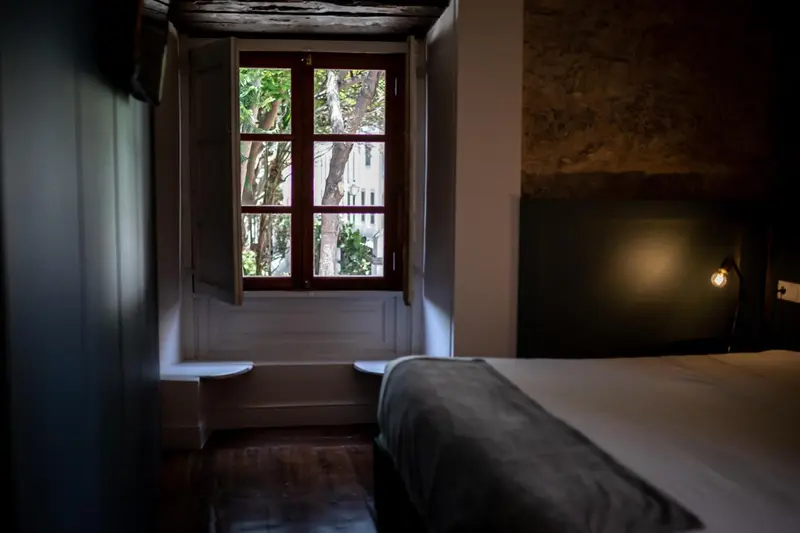 Une chambre lumineuse avec un lit et une fenêtre ouverte sur la végétation.