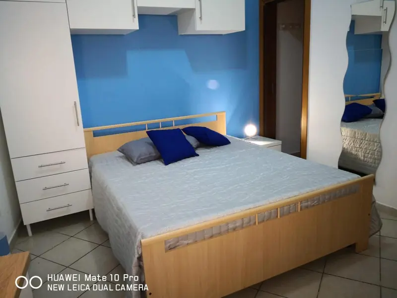 Une chambre lumineuse avec un grand lit et des coussins bleus.