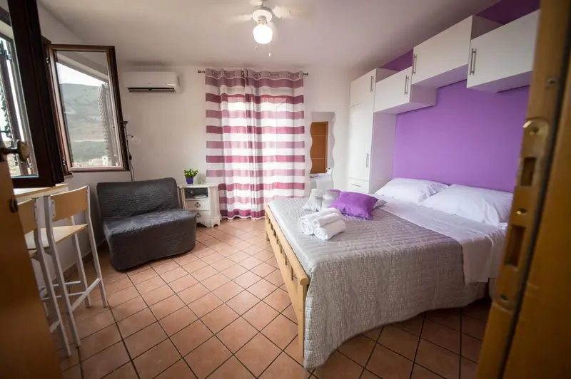 Une chambre lumineuse avec un lit double et un coin salon.