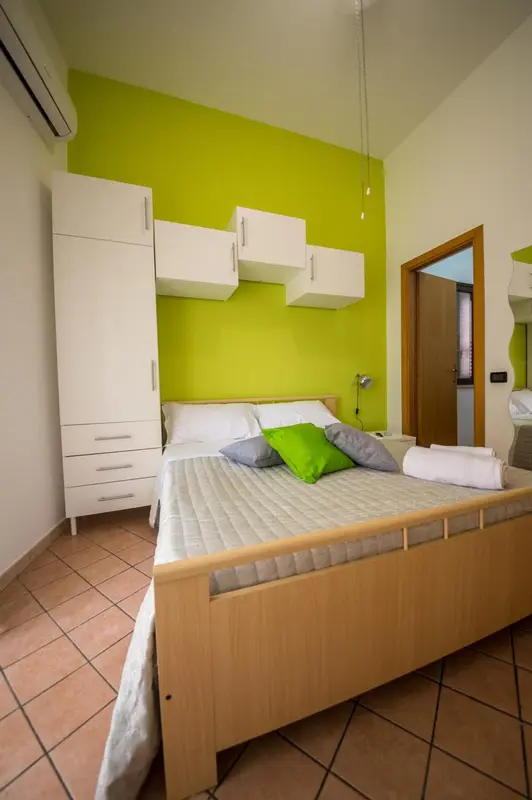 Une chambre lumineuse avec un lit fait et des rangements muraux.