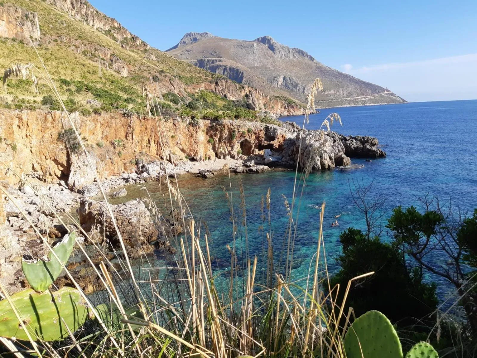 Côte rocheuse surplombant une crique turquoise et la mer.