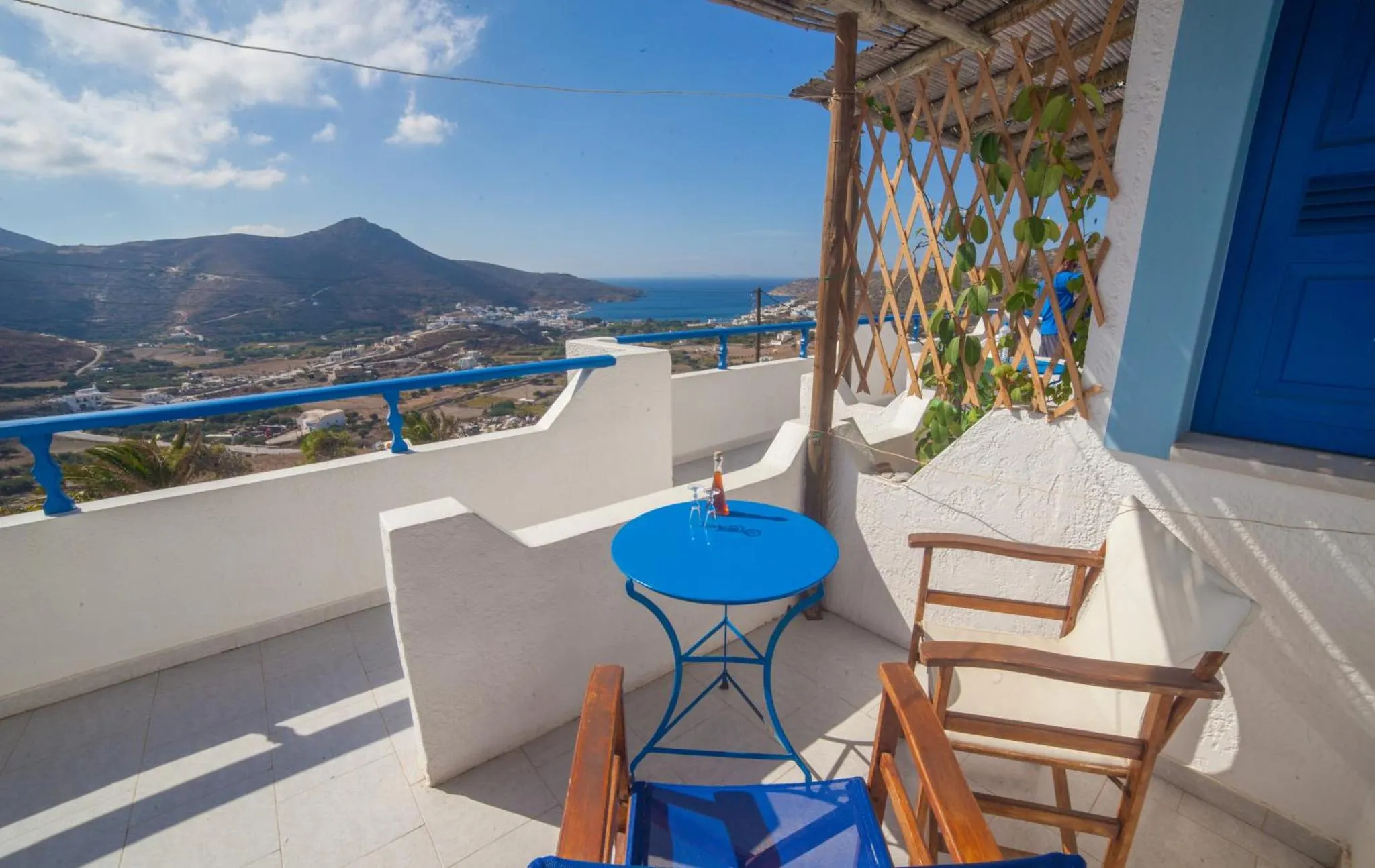 Terrasse avec table et chaises offrant une vue sur la mer et les montagnes.