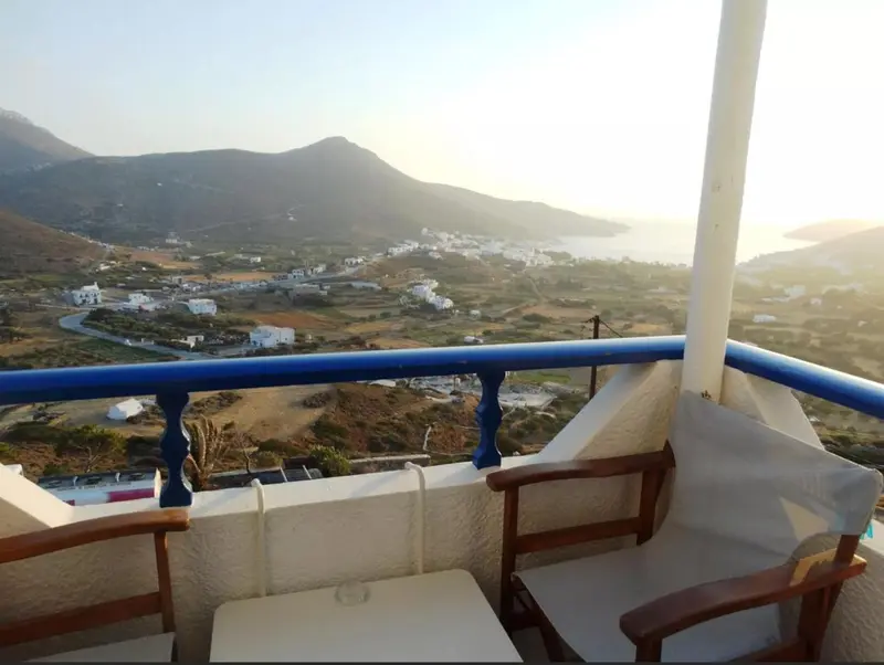 Vue panoramique sur un paysage montagneux et une ville côtière depuis une terrasse.